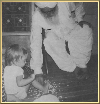 Kirpal Singh helps Mira Gerard pick up spilled parshad off the floor of the porch at Sawan Ashram, Delhi
